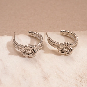 Détail de boucles d'oreilles C argentées avec nœud et texture torsadée sur pierre