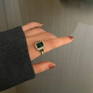 Close-up of vintage gold ring with emerald cut green gemstone and micro-diamond pavé