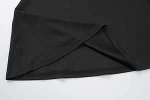 Gros plan de la couture à double aiguille et du tissu noir lisse sur l'ourlet de la robe