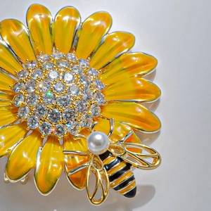 Macro shot of enamel sunflower bee brooch with white zircons and pearl detail