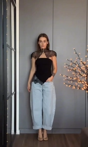 Détail du haut bustier noir avec châle en dentelle et jean bleu à revers