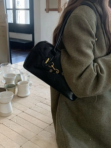 Detail view of black leather bowling bag with gold hardware worn on shoulder