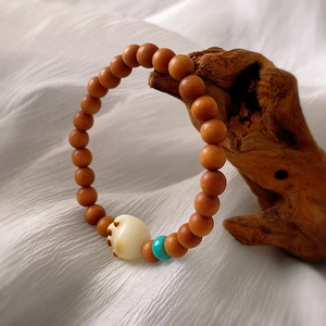 Close-up of vintage sandalwood beads with white acrylic cat paw charm on silk background