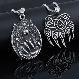 Detailed view of vintage silver bear paw and wolf head pendants on black background