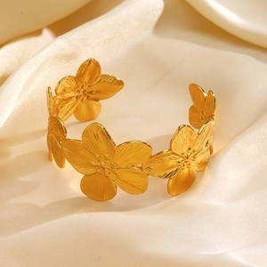 Elegante bracciale a fascia con fiori dorati e petali materici su sfondo seta