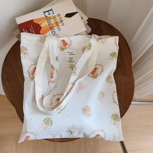 Vue détaillée du sac en coton blanc avec imprimé floral et portrait sur une table en bois