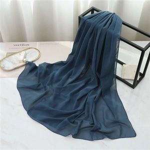 Detail of navy blue chiffon scarf with smooth texture displayed on marble surface