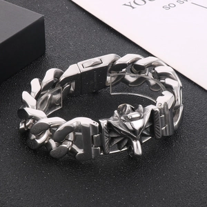 Detailed close-up of a masculine silver wolf head charm on a vintage steel Cuban chain bracelet