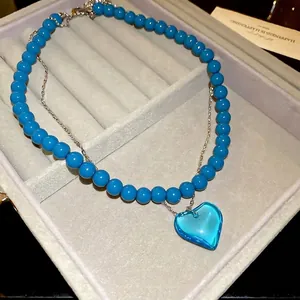 Elegant double-layered silver necklace featuring blue heart pendant and beaded chain detail