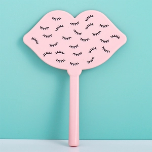 Detail view of pink lip-shaped handheld makeup mirror with black eyelash pattern on back