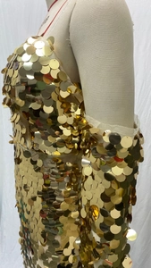 Detail view of gold oversized sequins in fish-scale pattern on mesh evening gown