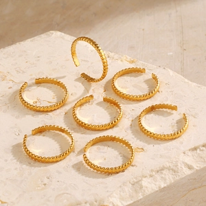 7-piece set of 18K gold plated twisted stacking rings on a stone display stand