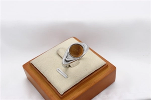 Macro shot of silver ring featuring a polished round tiger eye stone on a wooden display stand