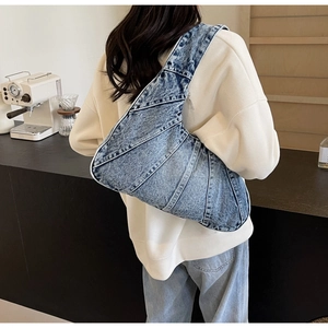 Vue détaillée du sac bandoulière en denim en forme de croissant avec coutures patchwork bleues