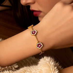Detail of 18k gold plated flower bracelet with red gems on a model wrist