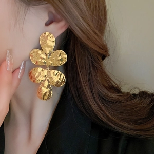 Macro detail of gold hammered metal flower earrings showing the textured fan-shaped petal design