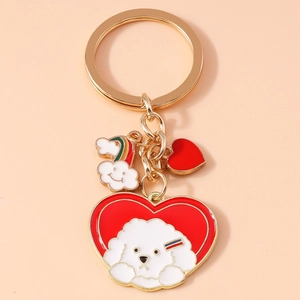 Detail of a gold keychain featuring a white Bichon dog on a red heart with a rainbow cloud