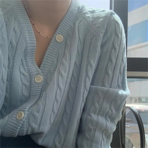 Detail of light blue cable knit cardigan featuring a V-neck and stylish white buttons