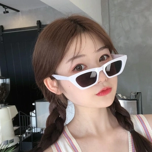 Close-up of white cat-eye sunglasses with thick frames and black lenses on female model