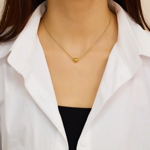 Détail d'un collier chaîne serpent plaqué or 18 carats avec pendentif perle ronde sur mannequin
