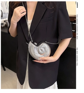Close-up of a silver snail-shaped metal crossbody bag with detailed radial texture