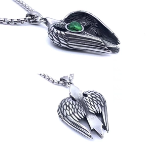 Macro shot of silver wing pendant with an inlaid green gemstone showing side and front view