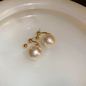 Vue macro de boucles d'oreilles perles vintage plaquées or sur une assiette blanche