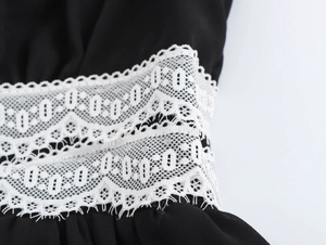 Macro detail of delicate white lace trim on elegant black V-neck chiffon dress fabric