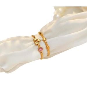 Minimalist gold plated stackable rings set with pink gemstone on white silk fabric