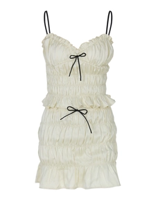 Sleeveless off-white ruffled dress with black bows and decorative hem details