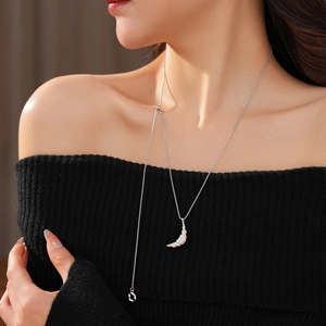 Detailed view of silver textured crescent moon pendant on long fringe sweater chain