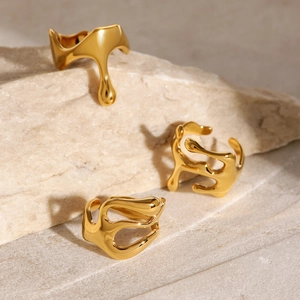 Detailed view of three gold melted-style rings displayed on a textured stone base