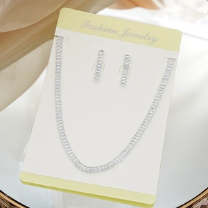 Macro shot of silver bridal jewelry set with rectangular cubic zirconia stones on silk