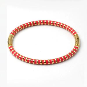 Detail view of red enamel and gold bamboo-textured stainless steel bangle clasp