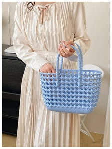 Sky blue woven jelly beach bag with hollow design carried by model in beige dress