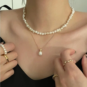 Minimalist 925 silver layered necklace with pearls and gold rings worn by a model