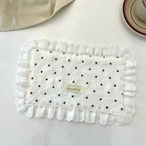 Close-up of a white cotton placemat with black heart patterns and delicate lace borders