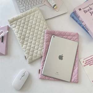 Detailed view of quilted diamond pattern laptop sleeves in beige and soft pink colors