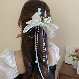 Detail of a large bow hair claw with elegant pearls and long ribbon tassels on hair