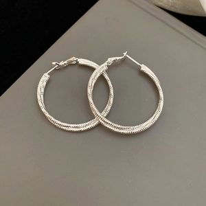 Detail of silver hoop earrings with textured facet finish and post back closure