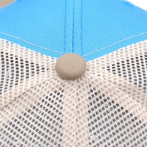 Detail of blue and white mesh trucker hat with beige top button and premium stitching