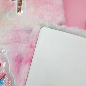 Close-up of pink and white plush notebook with soft faux fur texture and sequin detail