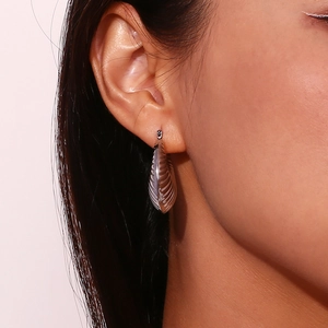 Close-up of thick silver textured hoop earrings with vertical ridges worn by a model