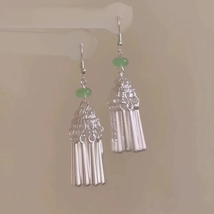 Boucles d'oreilles ethniques en argent avec perle verte et glands sur fond clair
