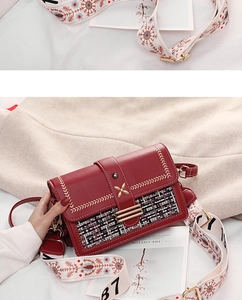 Detail of red PU leather and tweed patchwork handbag with embroidered wide strap