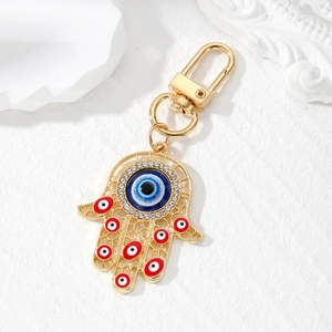 Vintage gold Hamsa Hand keychain with blue Evil Eye and sparkling crystals on white base