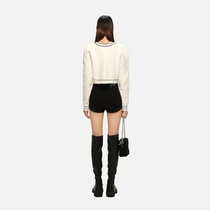 Rear view of a white knitted cardigan with black trim and plush texture detailing