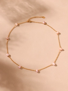 Detail of pink baroque pearls on a gold stainless steel chain with soft shadows