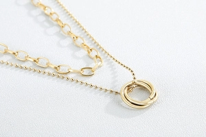Close-up of golden double-layer necklace with triple interlocking rings and beaded chain