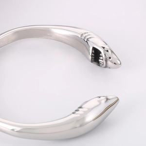 Macro shot of silver stainless steel open bangle with detailed shark head terminals